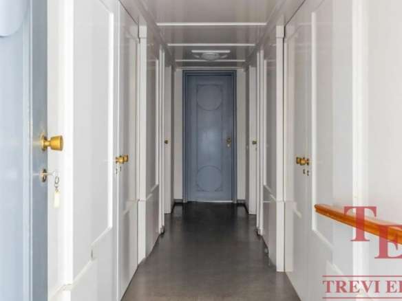 Элегантный коридор в роскошных апартаментах с белыми стенами и золотыми дверными ручками, создающий атмосферу изящества и комфорта в высококлассной недвижимости.