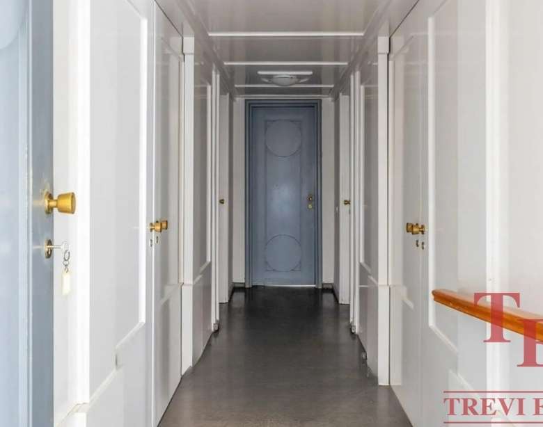 Элегантный коридор в роскошных апартаментах с белыми стенами и золотыми дверными ручками, создающий атмосферу изящества и комфорта в высококлассной недвижимости.