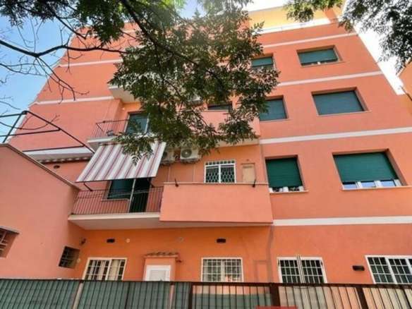 Высокоэтажное жилое здание в теплом оттенке с балконами и окнами, окруженное зеленью и деревьями, создает уютную атмосферу в престижном районе.