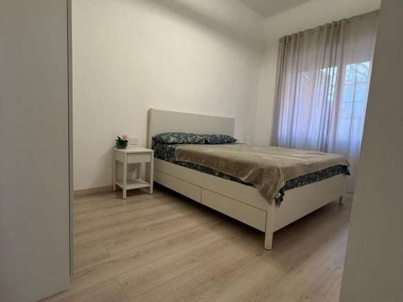 Современная спальня с мягким естественным освещением, минималистичный дизайн, белые стены, светлый деревянный пол, уютное окно с прозрачными шторами, стильная мебель для комфорта и уюта.