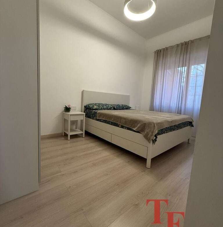 Современная спальня с мягким естественным освещением, минималистичный дизайн, белые стены, светлый деревянный пол, уютное окно с прозрачными шторами, стильная мебель для комфорта и уюта.