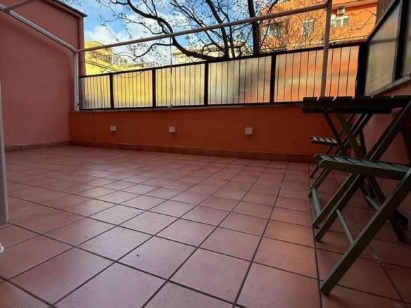 Просторная терраса с тёплой оттеночной плиткой, уютным ограждением и панорамным видом на город и деревья, идеально подходит для отдыха и развлечений под солнечным небом.