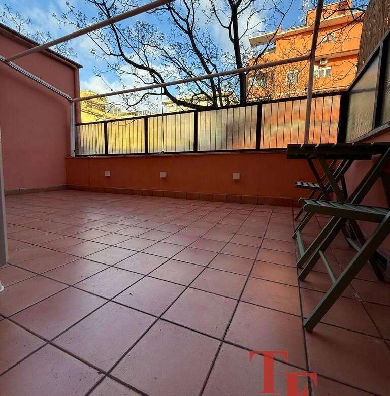 Просторная терраса с тёплой оттеночной плиткой, уютным ограждением и панорамным видом на город и деревья, идеально подходит для отдыха и развлечений под солнечным небом.