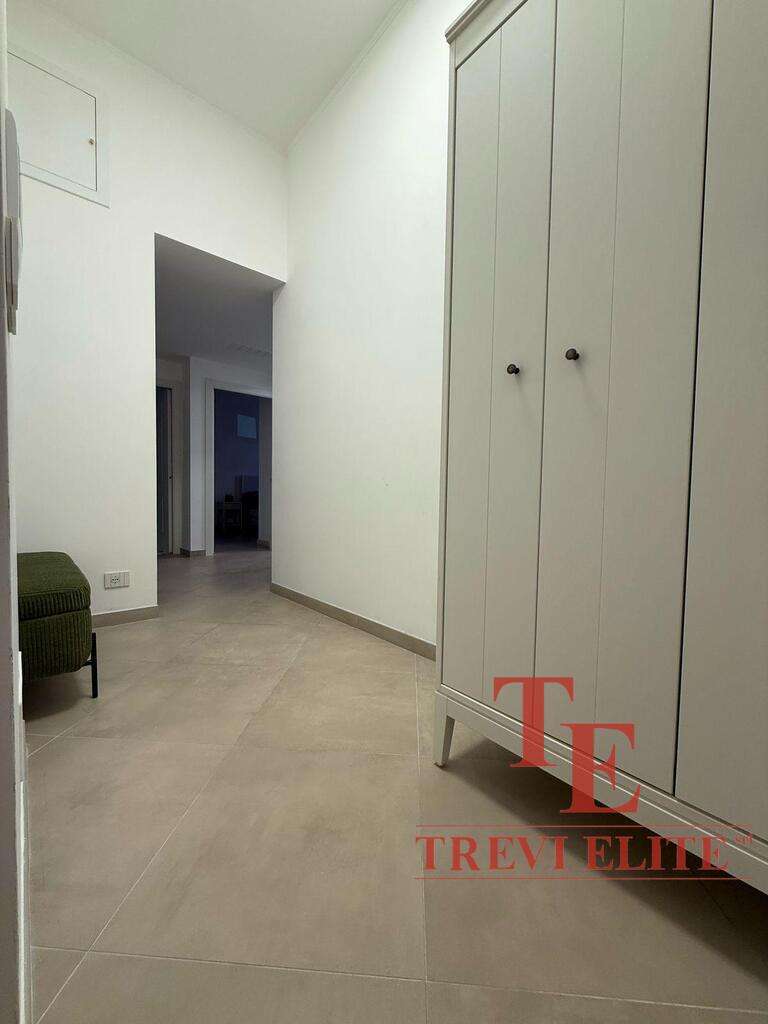 Просторный коридор с белыми стенами и вместительным шкафом, выполненным в светлом цвете, в современном стиле. Идеально подходит для хранения одежды и аксессуаров в элитной квартире.