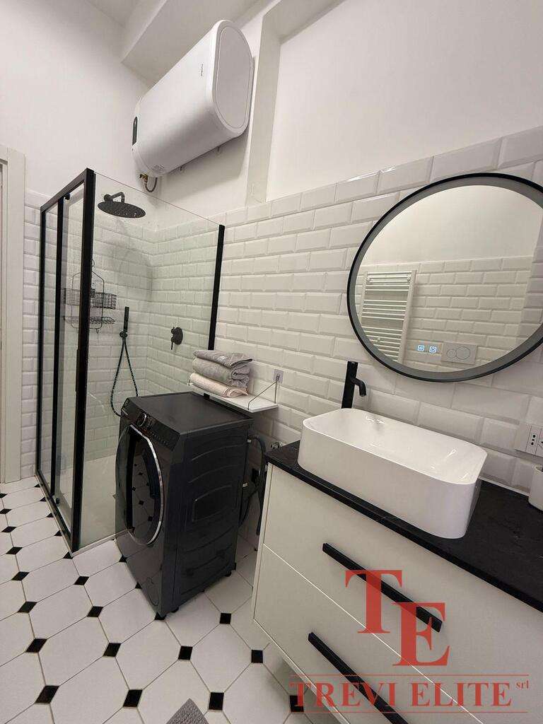 Современная ванная комната с душевой кабиной, раковиной в стиле лофт, стиральной машиной и элементами черного и белого дизайна. Идеально подходит для роскошного жилого пространства.