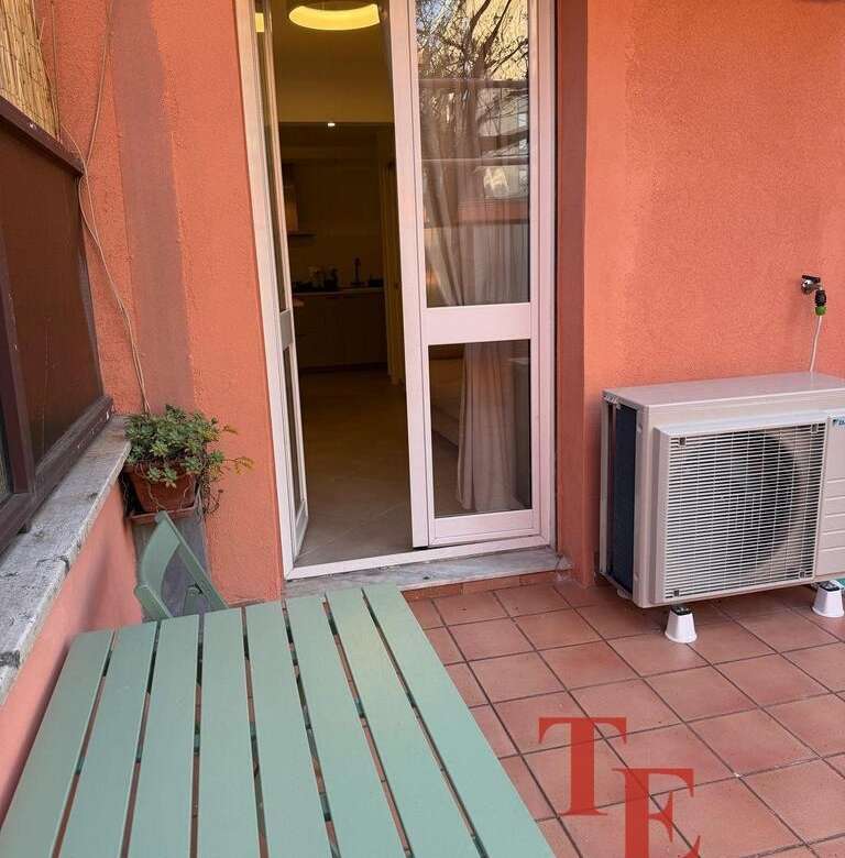 Современный балкон с уютной мебелью, выходящий на жилой дом с окнами, обеспечивающими естественное освещение и панорамный вид. Идеальное место для отдыха и наслаждения видом на город.