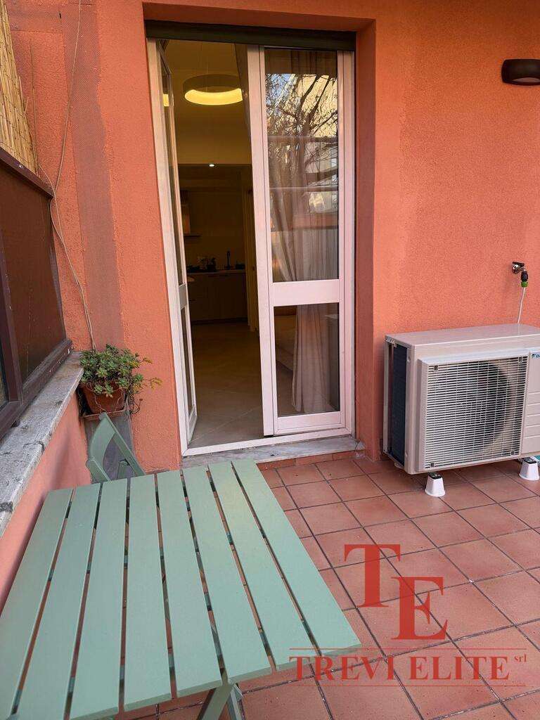 Современный балкон с уютной мебелью, выходящий на жилой дом с окнами, обеспечивающими естественное освещение и панорамный вид. Идеальное место для отдыха и наслаждения видом на город.