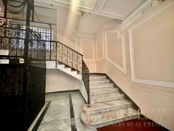 Элегантный интерьер лестничной клетки в роскошном здании с мраморными ступенями и декоративными панелями. Изысканный дизайн и стильный кованый балясина подчеркивают высокое качество недвижимости.