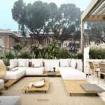 Элитная терраса с уютной белой мебелью и панорамным видом на зелень и городские дома, стильное оформление, создающее атмосферу роскоши и комфорта для высококлассного отдыха и развлечений.