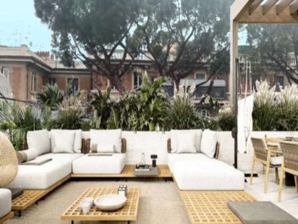 Элитная терраса с уютной белой мебелью и панорамным видом на зелень и городские дома, стильное оформление, создающее атмосферу роскоши и комфорта для высококлассного отдыха и развлечений.