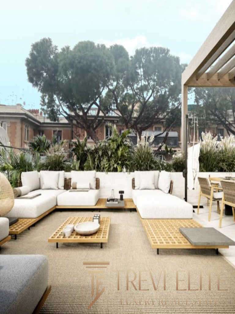 Элитная терраса с уютной белой мебелью и панорамным видом на зелень и городские дома, стильное оформление, создающее атмосферу роскоши и комфорта для высококлассного отдыха и развлечений.
