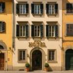 Элитное отельное здание в центре города, кирпичные стены, оригинальные оконные рамы с лоджиями, роскошная архитектура, уютные горшки с зеленью у входа. Отличное визуальное решение для привлекательного жилья высокого класса.