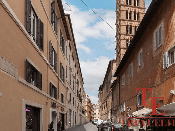 Улица в историческом центре Рима с видом на башню Аппиа. Старинные здания, узкая улица и уютная атмосфера, характерная для итальянской архитектуры и городской жизни.