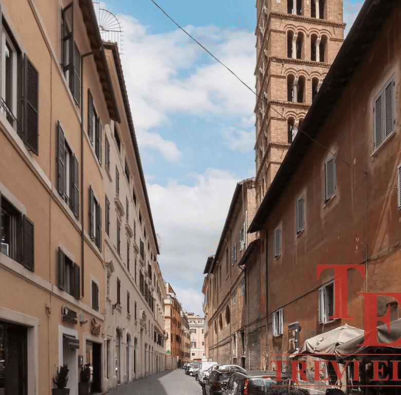 Улица в историческом центре Рима с видом на башню Аппиа. Старинные здания, узкая улица и уютная атмосфера, характерная для итальянской архитектуры и городской жизни.