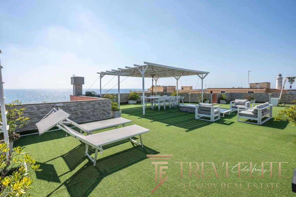 Роскошная терраса с видом на море, уютной зоной отдыха, шезлонгами и обеденной зоной под навесом, идеально подходит для роскошных вечеринок и релаксации на открытом воздухе.