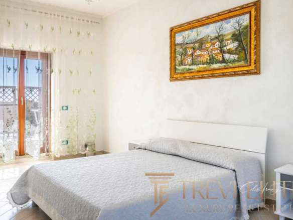 Роскошная спальня с видом на балкон и уютной атмосферой, элегантное оформление, светлые оттенки, современная мебель, картины в золотых рамах, множество солнечного света, подходящая для высококлассной недвижимости.