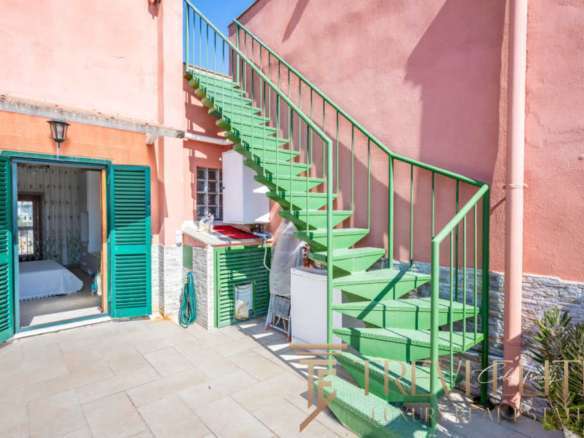 Кастомный зеленый наружный лестничный пролет на зеленой лестнице с чередующимися ступеньками и перилами, ведущий к верхним этажам роскошного здания в стиле итальянского курорта.