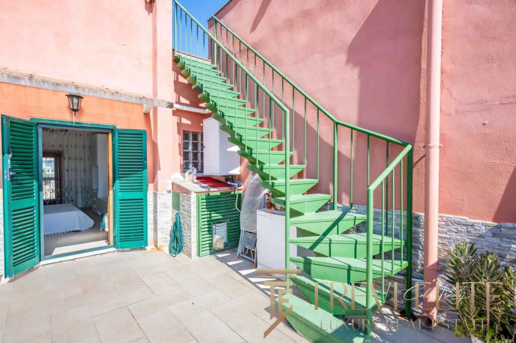 Кастомный зеленый наружный лестничный пролет на зеленой лестнице с чередующимися ступеньками и перилами, ведущий к верхним этажам роскошного здания в стиле итальянского курорта.