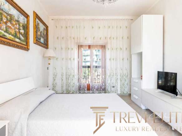 Элегантная спальня в современном стиле с белой мебелью и большими окнами, создающими яркую и просторную атмосферу. Идеальное пространство для отдыха и расслабления.