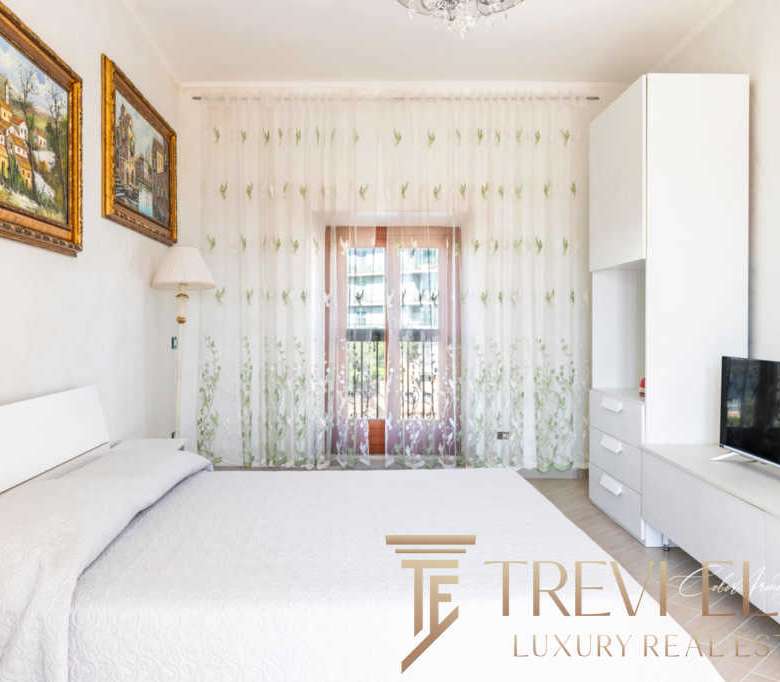 Элегантная спальня в современном стиле с белой мебелью и большими окнами, создающими яркую и просторную атмосферу. Идеальное пространство для отдыха и расслабления.