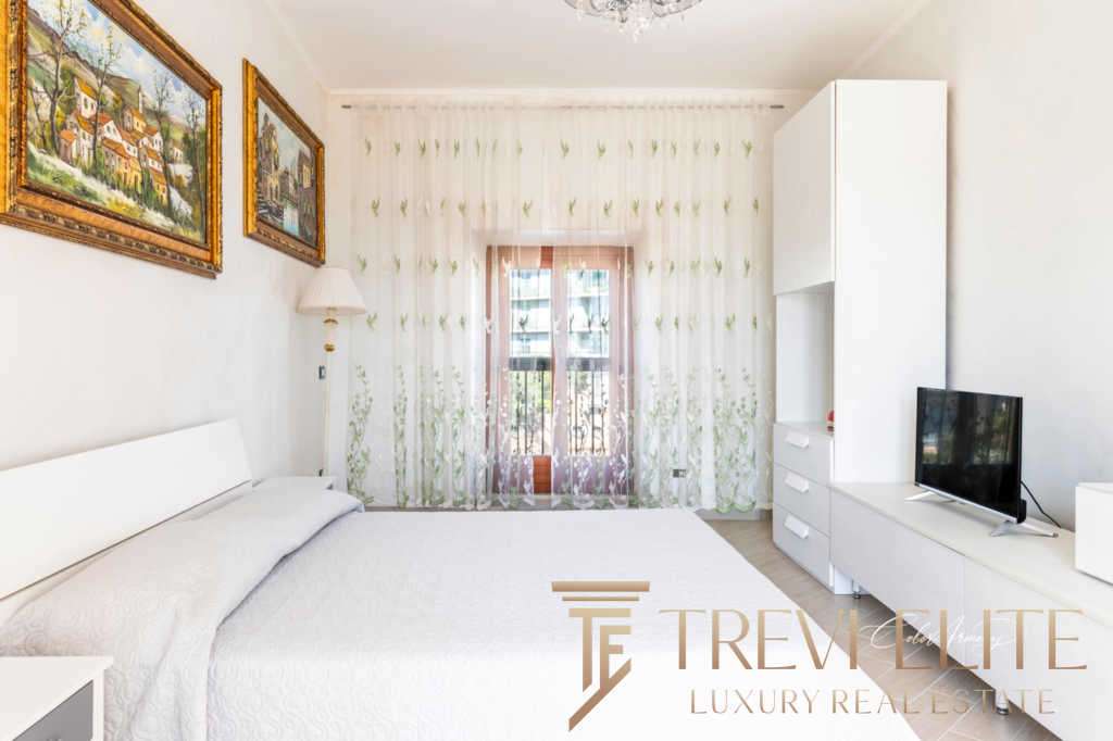 Элегантная спальня в современном стиле с белой мебелью и большими окнами, создающими яркую и просторную атмосферу. Идеальное пространство для отдыха и расслабления.