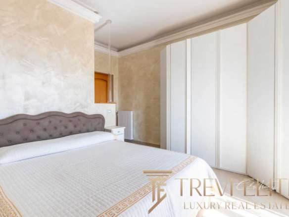 Роскошная спальня с мягкой изголовьем, просторным шкафом и светлыми стенами, подчеркивающими элитность недвижимости. Идеальное сочетание стиля и комфорта для высококлассной жизни.