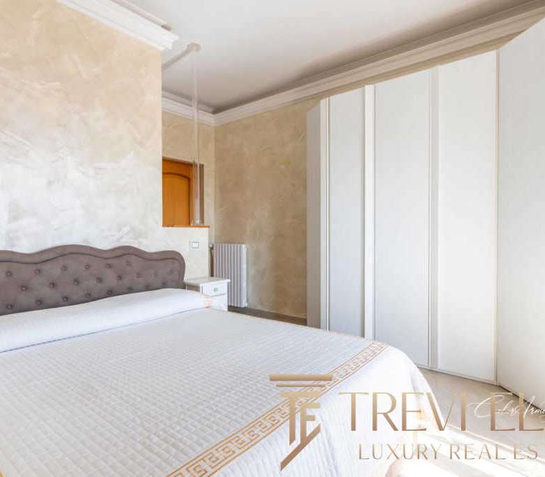 Роскошная спальня с мягкой изголовьем, просторным шкафом и светлыми стенами, подчеркивающими элитность недвижимости. Идеальное сочетание стиля и комфорта для высококлассной жизни.