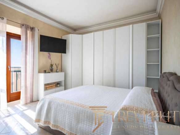 Уютная спальня в роскошной квартире с выходом на балкон, светлыми шторами и современным интерьером. Идеальное место для отдыха в элитной недвижимости от Треви Элит.