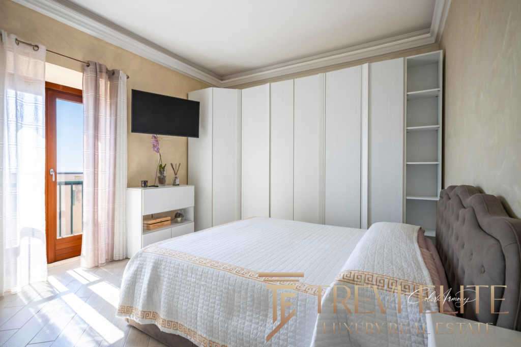 Уютная спальня в роскошной квартире с выходом на балкон, светлыми шторами и современным интерьером. Идеальное место для отдыха в элитной недвижимости от Треви Элит.