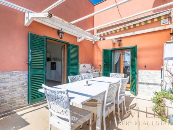 Уютная терраса с уютным мебельным набором и зеленым оформлением, идеальная для отдыха на свежем воздухе в роскошной вилле.