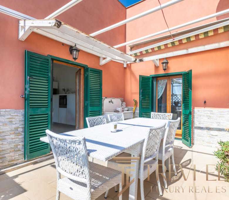 Уютная терраса с уютным мебельным набором и зеленым оформлением, идеальная для отдыха на свежем воздухе в роскошной вилле.