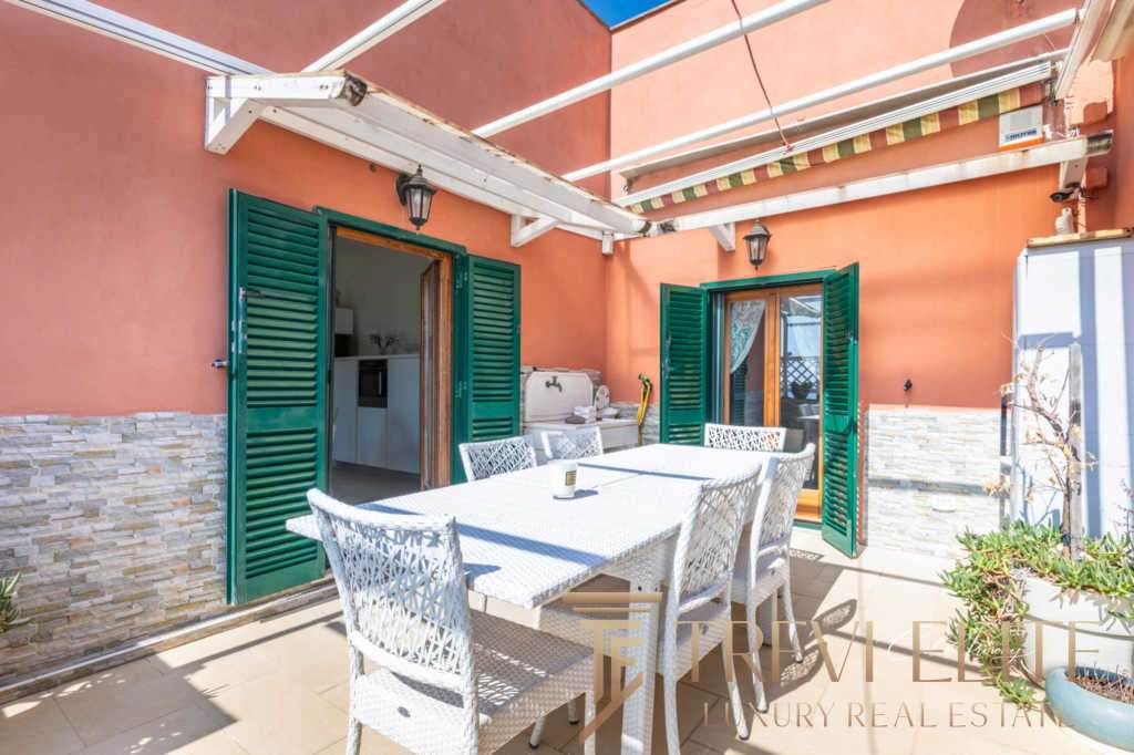 Уютная терраса с уютным мебельным набором и зеленым оформлением, идеальная для отдыха на свежем воздухе в роскошной вилле.