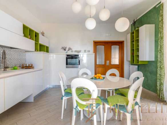 Элегантная кухня с белыми и зелеными акцентами, современная мебель и светлый интерьер, создающий уют и гармонию в роскошной недвижимости от Треви Элит.