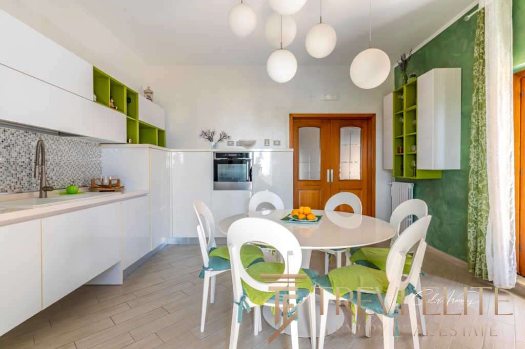 Элегантная кухня с белыми и зелеными акцентами, современная мебель и светлый интерьер, создающий уют и гармонию в роскошной недвижимости от Треви Элит.