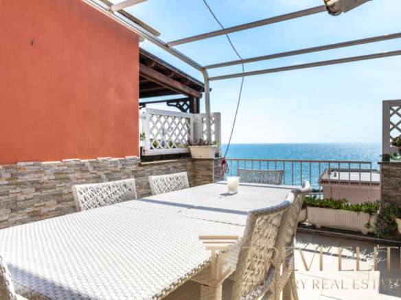 Уютная терраса с видом на море, оборудованная для отдыха на открытом воздухе. Идеальное место для наслаждения солнечными днями и морским пейзажем в центре итальянского жилого комплекса.