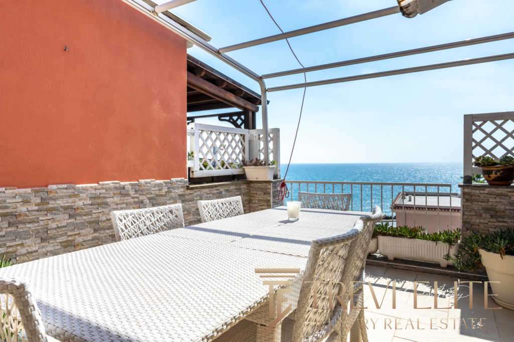 Уютная терраса с видом на море, оборудованная для отдыха на открытом воздухе. Идеальное место для наслаждения солнечными днями и морским пейзажем в центре итальянского жилого комплекса.