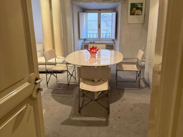 Уютная столовая с белым столом и четырьмя стульями у окна в светлом интерьере квартиры премиум-класса.