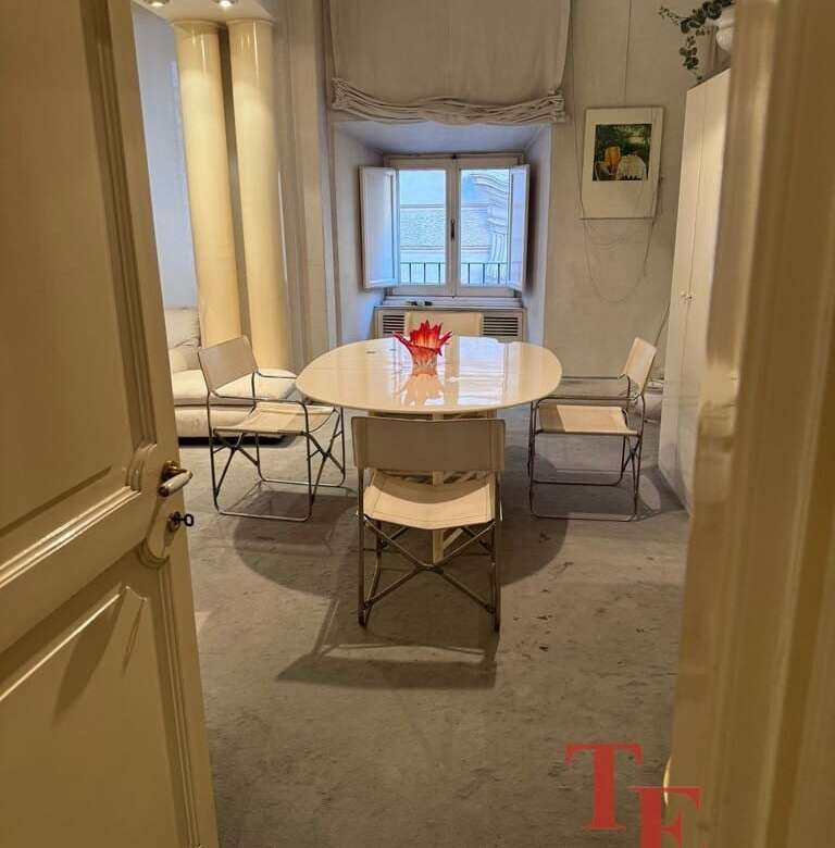 Уютная столовая с белым столом и четырьмя стульями у окна в светлом интерьере квартиры премиум-класса.