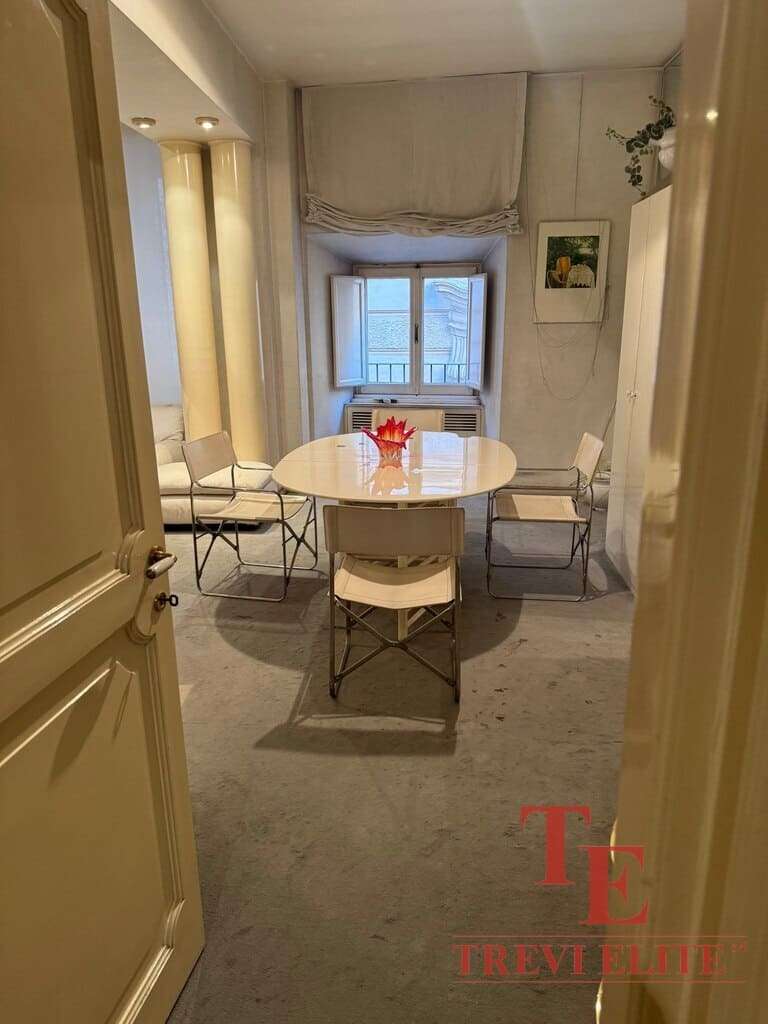 Уютная столовая с белым столом и четырьмя стульями у окна в светлом интерьере квартиры премиум-класса.