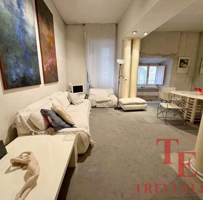 Современная гостиная в элитной недвижимости, дизайн с белой мебелью и художественными картинами, уютная зона отдыха для семейного уюта и высокого комфорта.