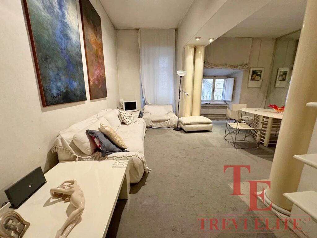 Современная гостиная в элитной недвижимости, дизайн с белой мебелью и художественными картинами, уютная зона отдыха для семейного уюта и высокого комфорта.