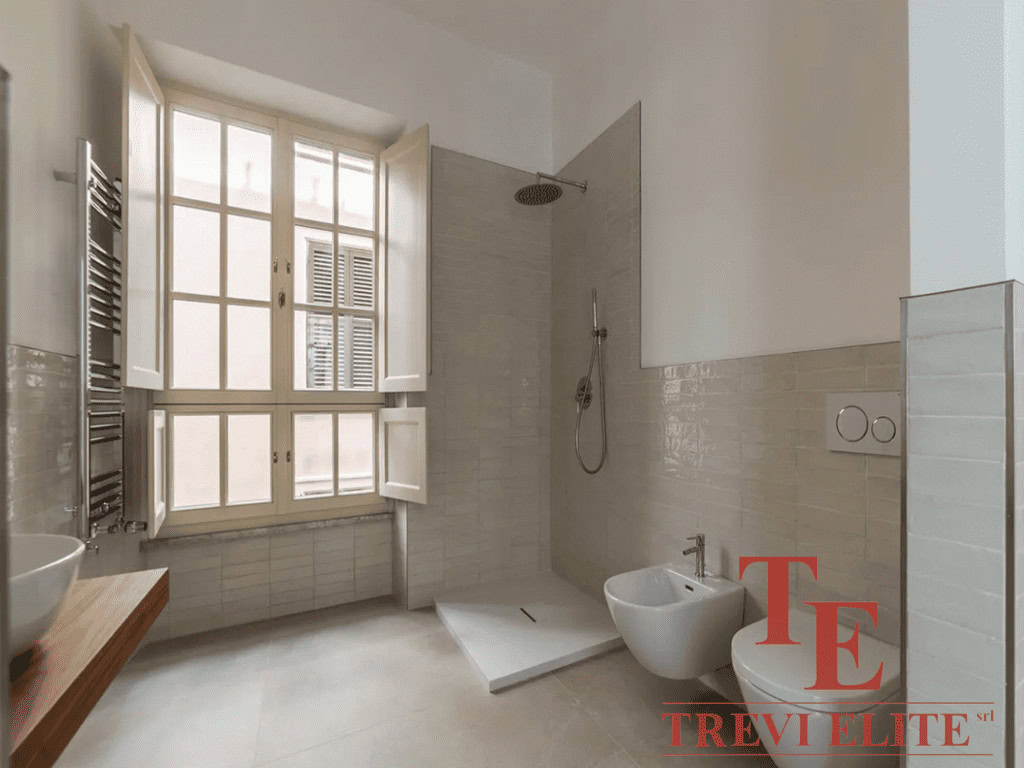 Современный дизайнерский санузел с большой природной подсветкой, окна с деревянными рамами и качественной отделкой. Ванная комната в элитной недвижимости с стильной мебелью и отделочными материалами.