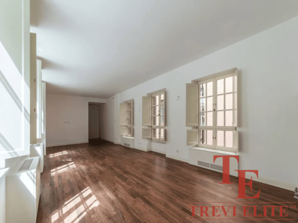 Современная просторная гостиная в роскошной недвижимости с большими окнами и деревянным полом, подчеркнутая светлым интерьером для высокого комфорта жизни.