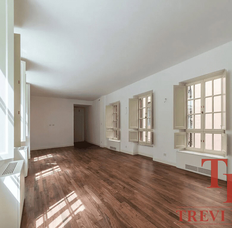 Современная просторная гостиная в роскошной недвижимости с большими окнами и деревянным полом, подчеркнутая светлым интерьером для высокого комфорта жизни.