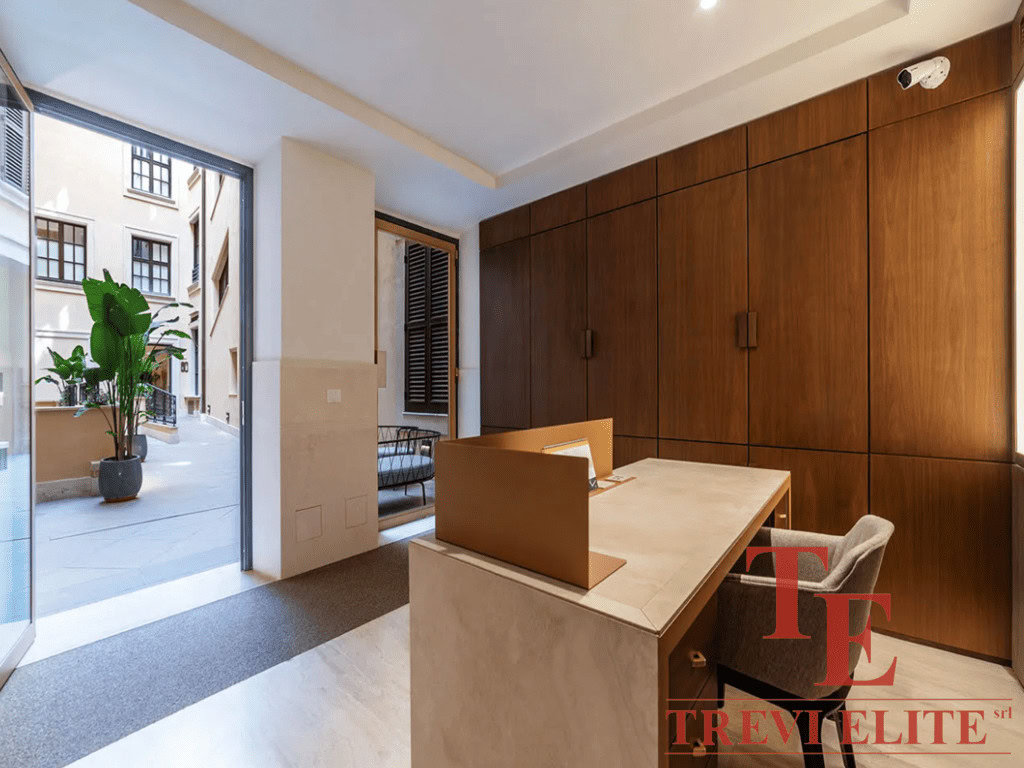 Современное интеррьерное пространство с деревянными панелями, просторным рабочим столом и выходом на уютный балкон с растениями. Идеальный дизайн для элитной недвижимости в Италии и мире.