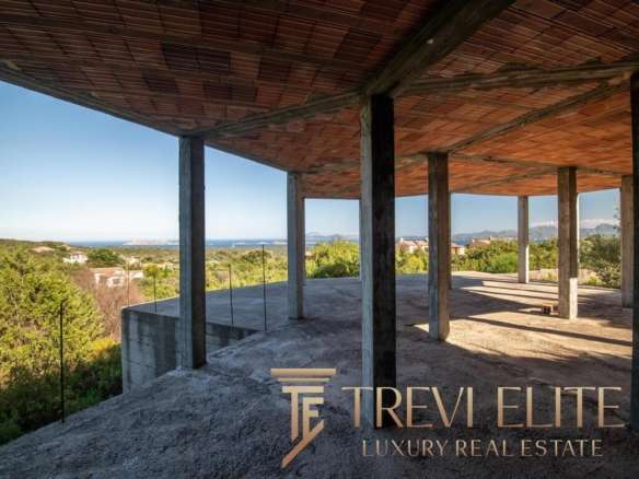 Современный строительный каркас на фоне живописного пейзажа, видны горы, зелень и море, подчеркивающие эксклюзивность и потенциал объекта высокой недвижимости.