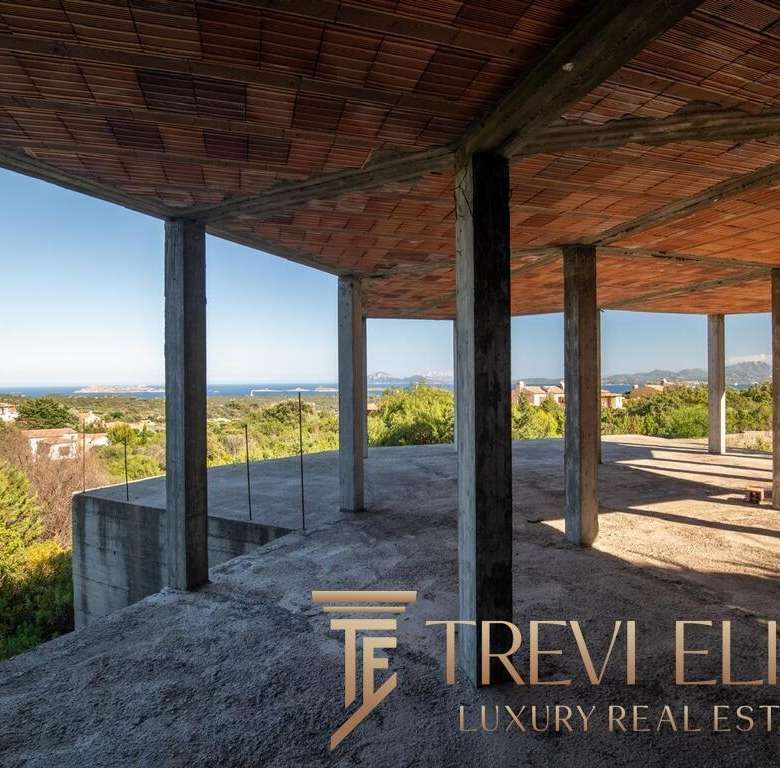 Современный строительный каркас на фоне живописного пейзажа, видны горы, зелень и море, подчеркивающие эксклюзивность и потенциал объекта высокой недвижимости.