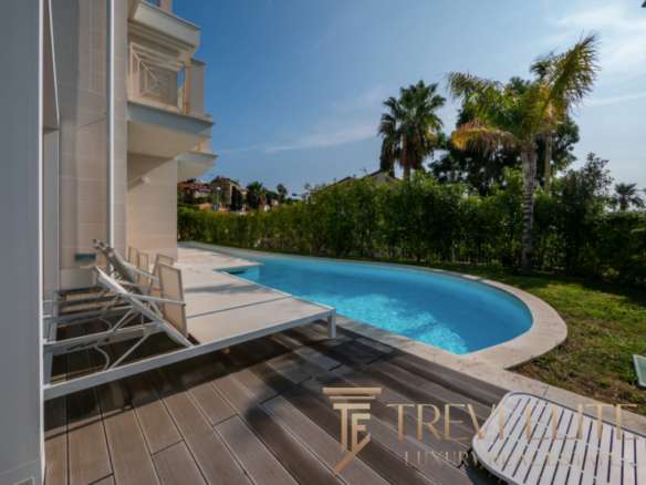 Элитная частная резиденция с изогнутым бассейном и зоной отдыха на террасе, окруженная пальмами и зеленью, стильное оформление недвижимости для роскошного образа жизни.