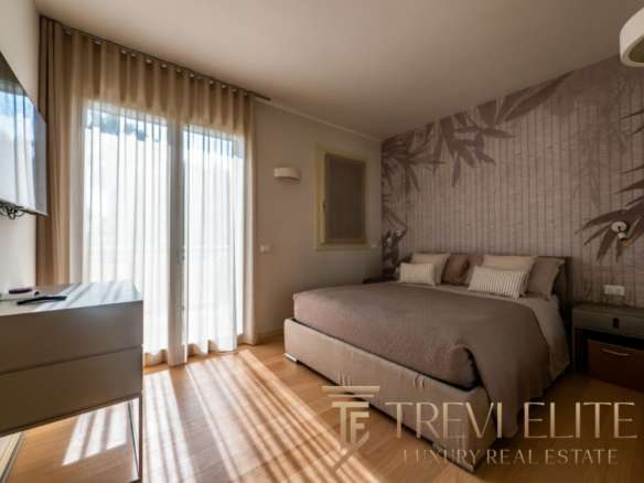 Роскошная спальня в элитной недвижимости, светлый интерьер с видом на окно и стильным дизайном стен, создающая атмосферу уюта и комфорта для высококлассного жилья.