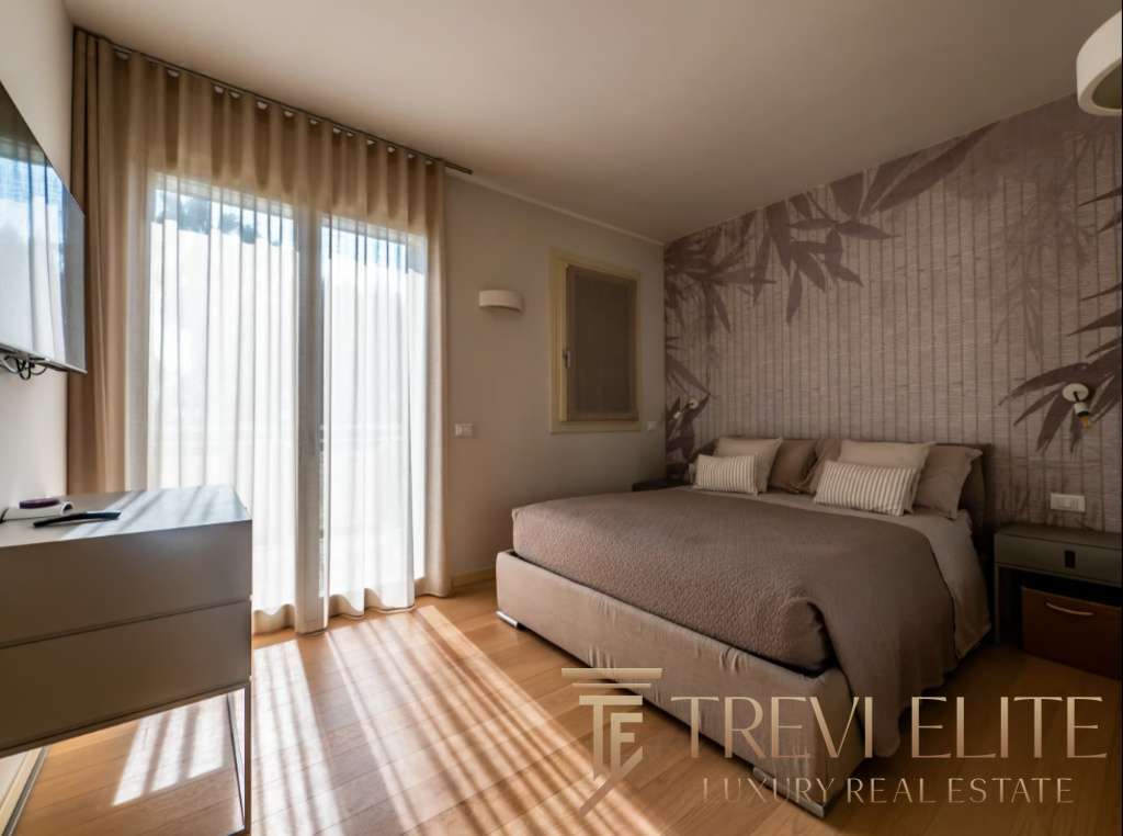 Роскошная спальня в элитной недвижимости, светлый интерьер с видом на окно и стильным дизайном стен, создающая атмосферу уюта и комфорта для высококлассного жилья.